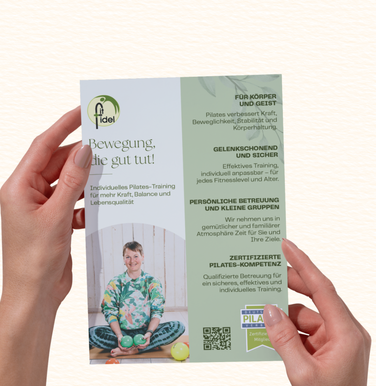 Hände halten ein Informationsblatt mit einem Kind in bunter Kleidung und verschiedenen Texten.
